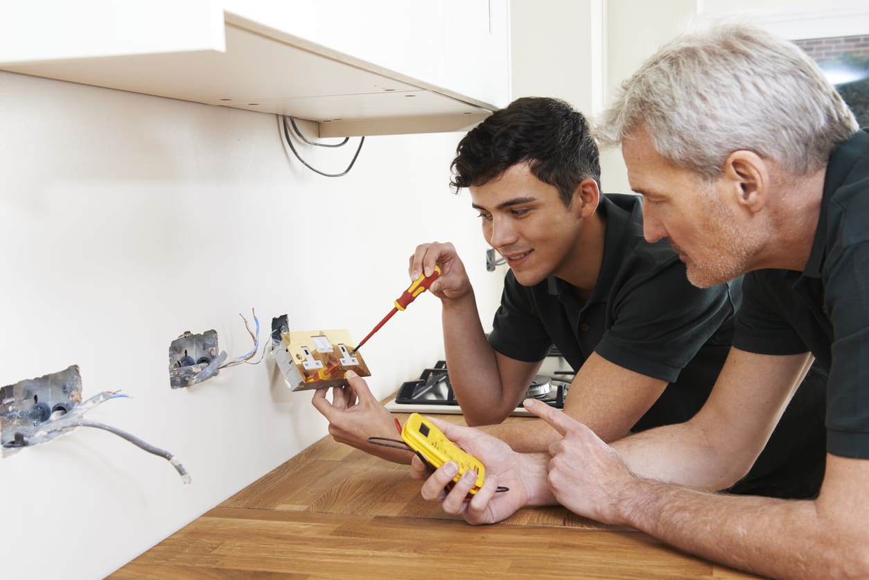 Electrician With Apprentice Working In New Home